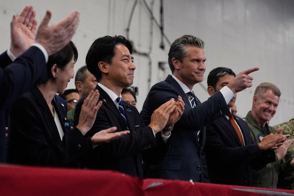 U.S. Defense Secretary Pete Hegseth, center right, with Japanese Prime Minister Sanae Takaichi, left, and Defense Minister Shinjiro Koizumi, gestures as they listen to President Donald Trump speak to members of the military aboard the USS George Washington, an aircraft carrier docked at an American naval base, in Yokosuka, south of Tokyo, Tuesday, Oct. 28, 2025. (AP Photo/Mark Schiefelbein)