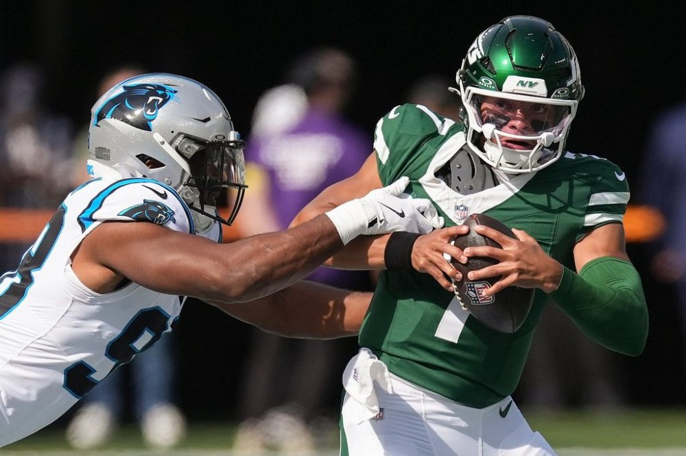 New York Jets quarterback Justin Fields (7) tries to avoid a tackle by Carolina Panthers linebacker D.J. Wonnum (98) during the first quarter of an NFL football game, Sunday, Oct. 19, 2025, in East Rutherford, N.J. (AP Photo/Seth Wenig)