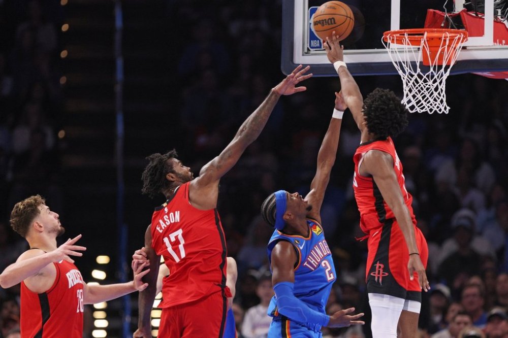 Houston Rockets guard Amen Thompson, right, blocks a shot by Oklahoma City Thunder guard Shai Gilgeous-Alexander (2) near Rockets forward Tari Eason (17) and center Alperen Sengun, left, during the second half of an NBA basketball game Tuesday, Oct. 21, 2025, in Oklahoma City. (AP Photo/Nate Billings)