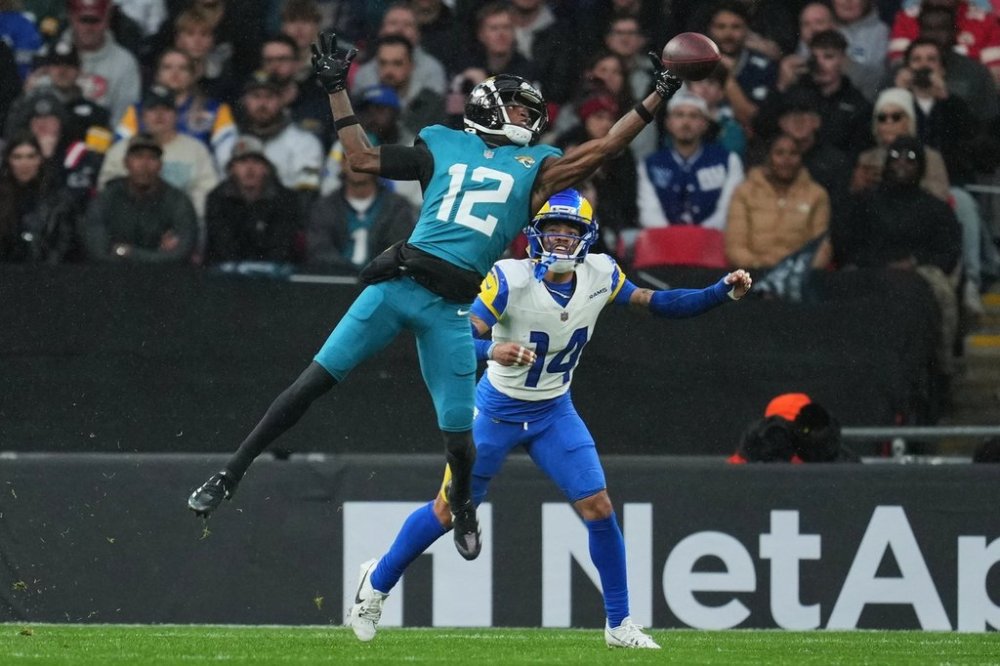 Jacksonville Jaguars wide receiver Travis Hunter (12) reaches to catch the ball as Los Angeles Rams cornerback Cobie Durant (14) challenges during the first half of an NFL football game between the Los Angeles Rams and the Jacksonville Jaguars in London, Sunday, Oct. 19, 2025. (AP Photo/Kin Cheung)