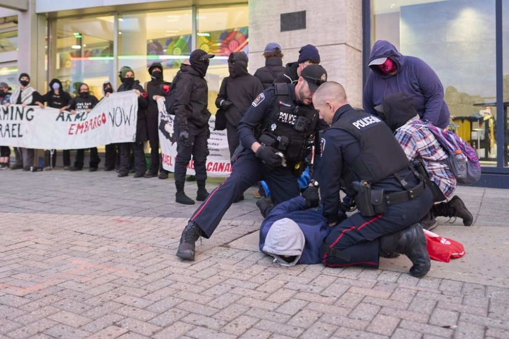 A pro-Palestinian protester is taken into custody by London Police after attempting to block access to the Best Defence Conference at RBC Place in London, Ont., on Tuesday, Oct. 21, 2025.THE CANADIAN PRESS/Geoff Robins
