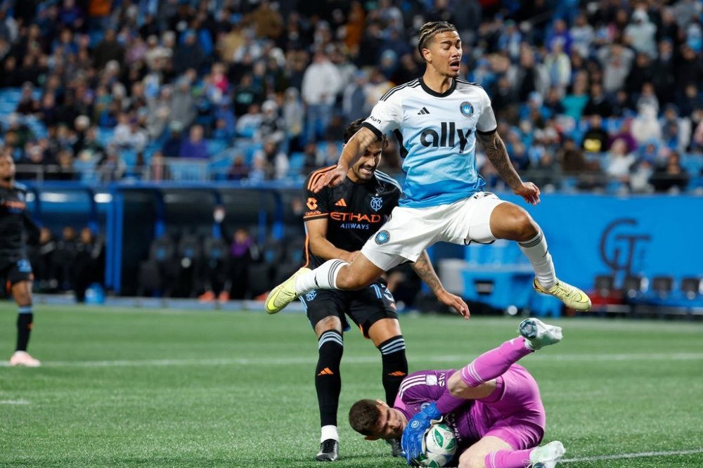Charlotte FC forward Idan Toklomati leaps over New York City FC goalkeeper Matt Freese (49) as Freese blocks Toklomati's shot during the second half of Game 1 in the first round of MLS soccer's Eastern Conference playoffs in Charlotte, N.C., Tuesday, Oct. 28, 2025. (AP Photo/Nell Redmond)