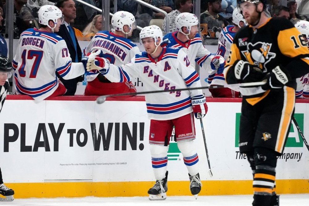 New York Rangers' Adam Fox (23) celebrates as he returns to the bench after scoring the first of his two goals during the second period of an NHL hockey game against the Pittsburgh Penguins in Pittsburgh, Saturday, Oct. 11, 2025. (AP Photo/Gene J. Puskar)