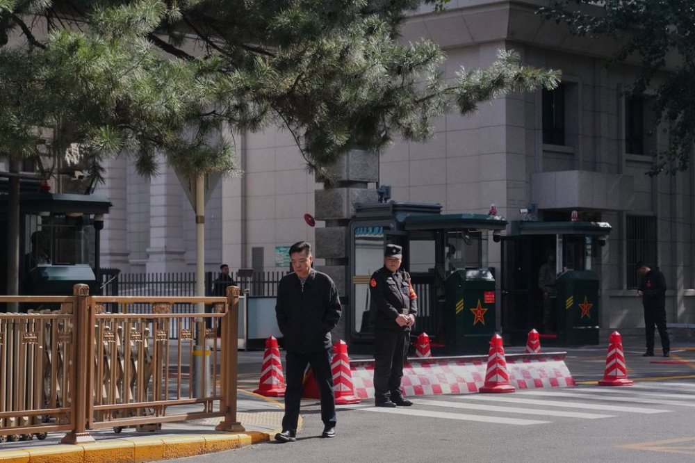 A man walks by Chinese security personnel guarding the entrance to the Jingxi Hotel where the Communist Party's Central Committee is holding its fourth plenum, in Beijing, Monday, Oct. 20, 2025. (AP Photo/Andy Wong)