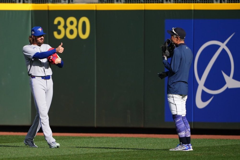 Toronto Blue Jays pitcher Kevin Gausman, left, gives a thumbs-up while greeting National Baseball Hall of Fame member and former Seattle Mariners right-fielder Ichiro Suzuki before Game 3 of baseball's American League Championship Series on Oct. 15, 2025, in Seattle. (AP Photo/Lindsey Wasson)
