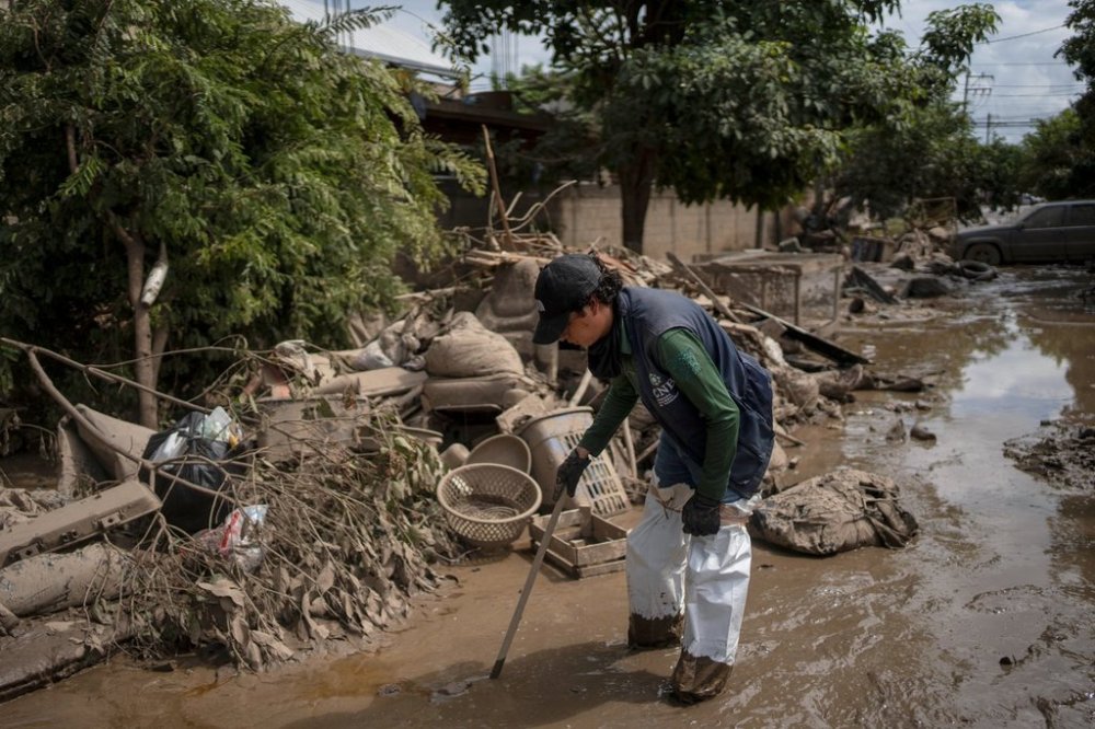 A public official searches for missing people on a mud-covered street in Poza Rica, Veracruz state, Mexico, on Tuesday, Oct. 14, 2025, after landslides and torrential rain. (AP Photo/Felix Marquez)