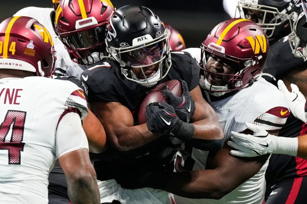 Atlanta Falcons running back Bijan Robinson, center, is tackled by Washington Commanders defenders during the first half of an NFL football game, Sunday, Sept. 28, 2025, in Atlanta. (AP Photo/Brynn Anderson)