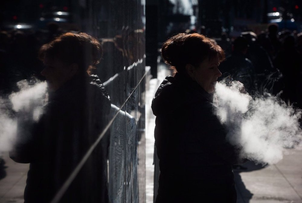 A woman exhales while smoking a vaporizer outside an office tower in downtown Vancouver, Tuesday, Feb. 28, 2017. THE CANADIAN PRESS/Darryl Dyck