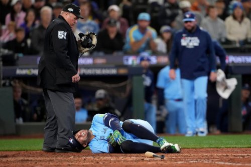 Toronto Blue Jays designated hitter George Springer falls after being hit by a pitch in the seventh inning of Game 5 against the Mariners in baseball's American League Championship Series on Oct. 17, 2025, in Seattle. (AP Photo/Lindsey Wasson)
