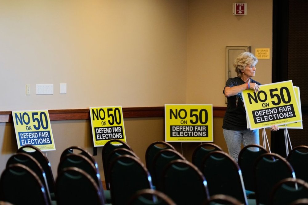 Brenda Haynes places signs throughout a conference room before a No on Prop 50 rally in Redding, Calif., Tuesday, Oct. 21, 2025. (AP Photo/Godofredo A. Vásquez)