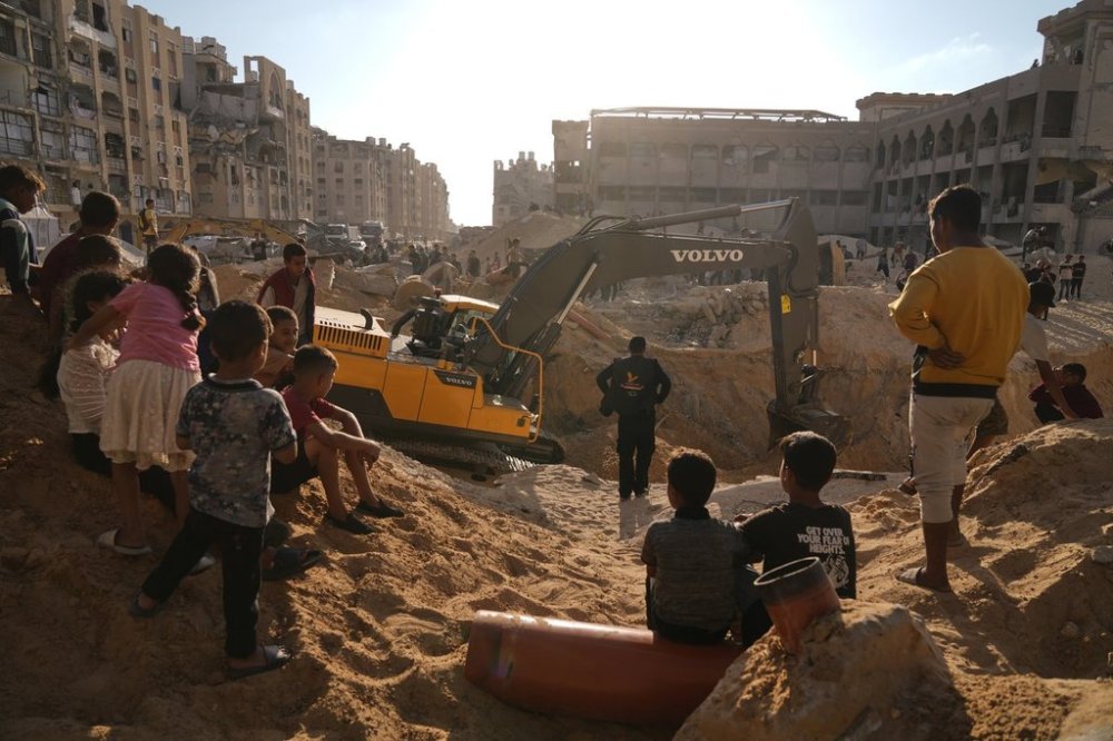 Palestinians watch machinery and some workers from Egypt searching for the bodies of hostages at Hamad City, in Khan Younis, southern Gaza Strip, Sunday, Oct. 26, 2025. (AP Photo/Jehad Alshrafi)