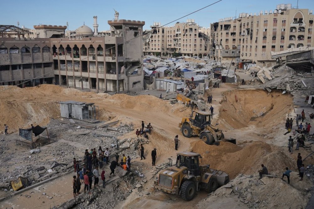 Palestinians watch members of the Hamas militant group searching for bodies of the hostages in an area in Hamad City, Khan Younis, in the southern Gaza Strip, Saturday, Oct. 18, 2025. (AP Photo/Jehad Alshrafi)