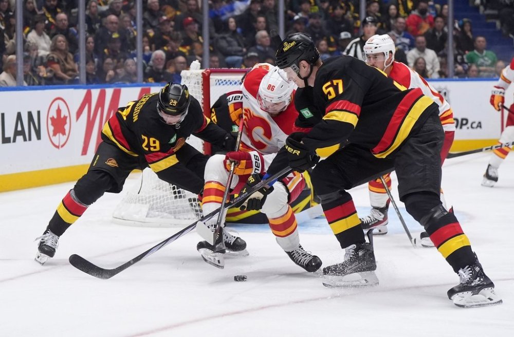 Calgary Flames' Joel Farabee (86) vies for the puck against Vancouver Canucks' Marcus Pettersson (29) and Tyler Myers (57) during the second period of an NHL hockey game in Vancouver, on Thursday, October 9, 2025. THE CANADIAN PRESS/Darryl Dyck