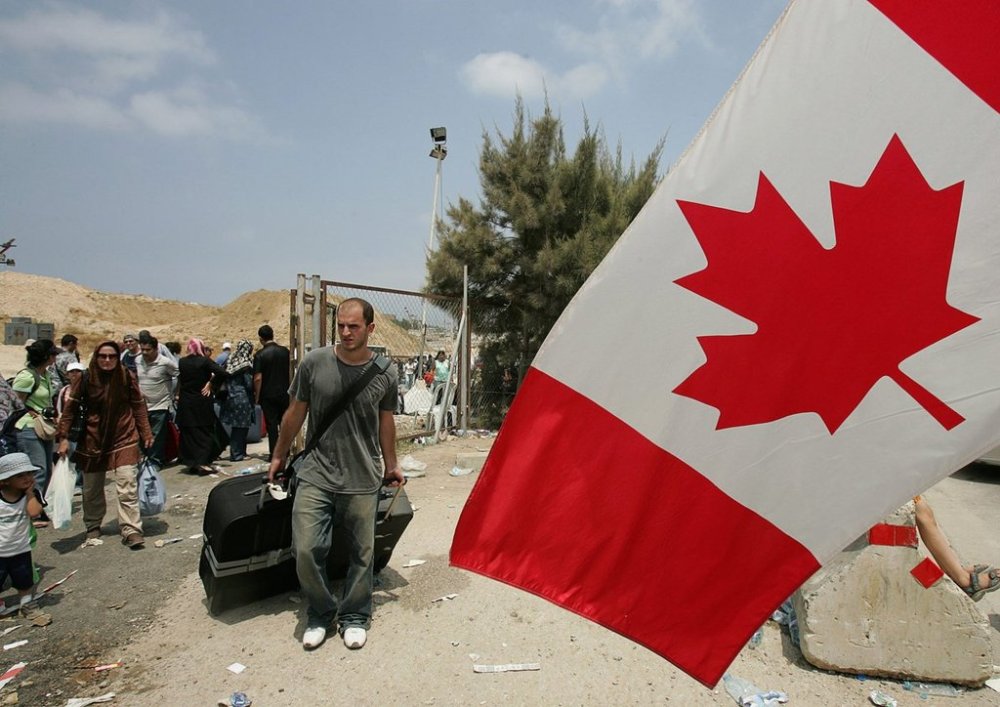Canadian citizens stand next to their national flag, as they wait to be evacuated by buses organized by the Canadian embassy, in downtown Beirut, Lebanon, Wednesday, July 19, 2006. (AP Photo/Hussein Malla)