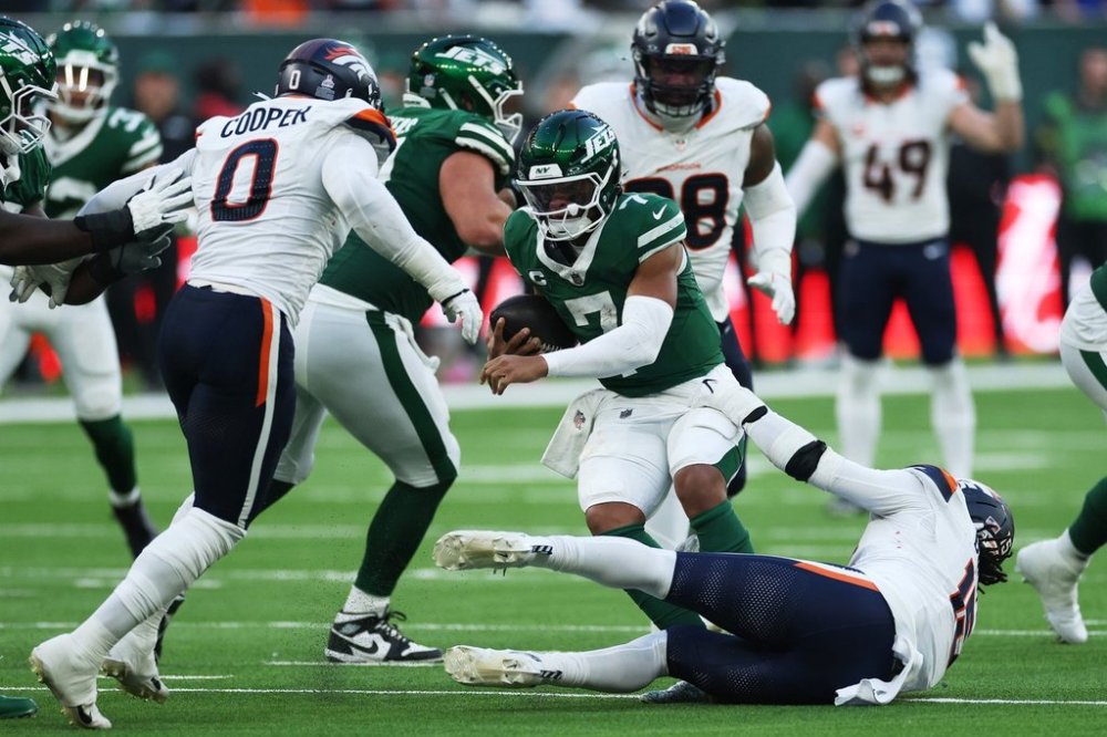 New York Jets quarterback Justin Fields, center, is sacked by Denver Broncos linebackers Jonathon Cooper, left, and Alex Singleton in the second half of an NFL football game Sunday, Oct. 12, 2025, in London. (AP Photo/Ian Walton)