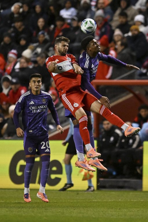 Orlando City's Alex Freeman, right, battles Chicago Fire's Hugo Cuypers, center, for a header during the first half of an MLS soccer wild-card playoff match Wednesday, Oct. 22, 2025, in Bridgeview, Ill. (AP Photo/Paul Beaty)
