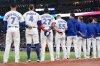 Toronto Blue Jays' Isiah Kiner-Falefa (7), George Springer (4), Vladimir Guerrero Jr. (27), Tyler Heineman (55) and members of the bullpen line up for the singing of the national anthems ahead of first inning MLB American League Championship Series game 7 baseball action against the Seattle Mariners in Toronto, Monday, Oct. 20, 2025. THE CANADIAN PRESS/Nathan Denette