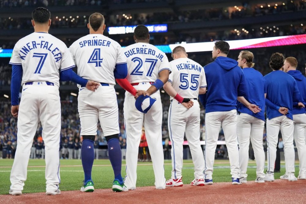 Toronto Blue Jays' Isiah Kiner-Falefa (7), George Springer (4), Vladimir Guerrero Jr. (27), Tyler Heineman (55) and members of the bullpen line up for the singing of the national anthems ahead of first inning MLB American League Championship Series game 7 baseball action against the Seattle Mariners in Toronto, Monday, Oct. 20, 2025. THE CANADIAN PRESS/Nathan Denette