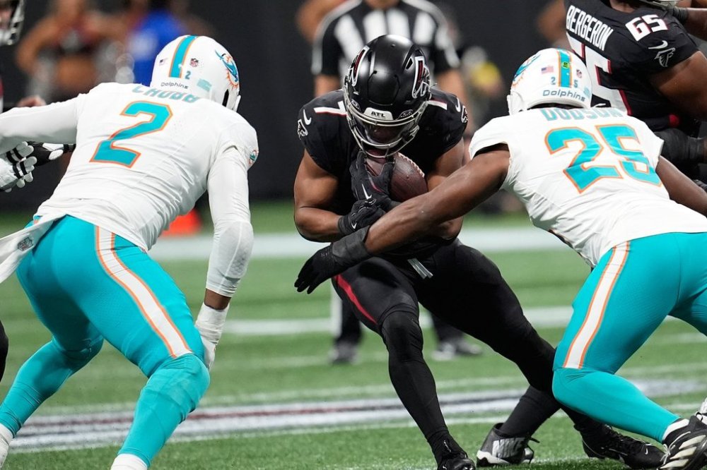 Atlanta Falcons running back Bijan Robinson (7) runs as Miami Dolphins linebacker Bradley Chubb (2) and linebacker Tyrel Dodson (25) defend during the first half of an NFL football game Sunday, Oct. 26, 2025, in Atlanta. (AP Photo/Mike Stewart)