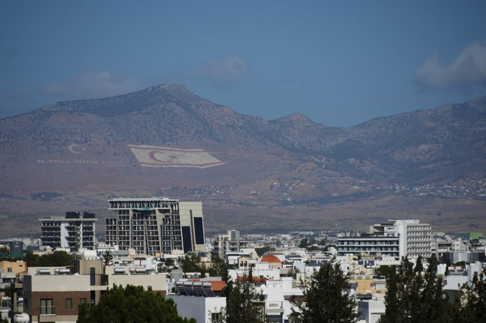 A view of buildings in the divided capital Nicosia, with a Turkish breakway giant flag painted in the background, right, and a Turkish crescent, left, on the Pentadahtilos mountain in the Turkish occupied area at northern part of the island of Cyprus, Friday, Oct. 24, 2025. (AP Photo/Petros Karadjias)