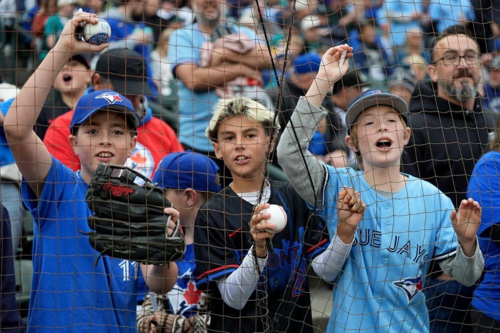 Toronto Blue Jays fans with balls and markers hope to get an autograph prior to first inning MLB American League Championship Series Game 4 baseball action between the Seattle Mariners and the Toronto Blue Jays, in Seattle, Thursday, Oct. 16, 2025. THE CANADIAN PRESS/Frank Gunn