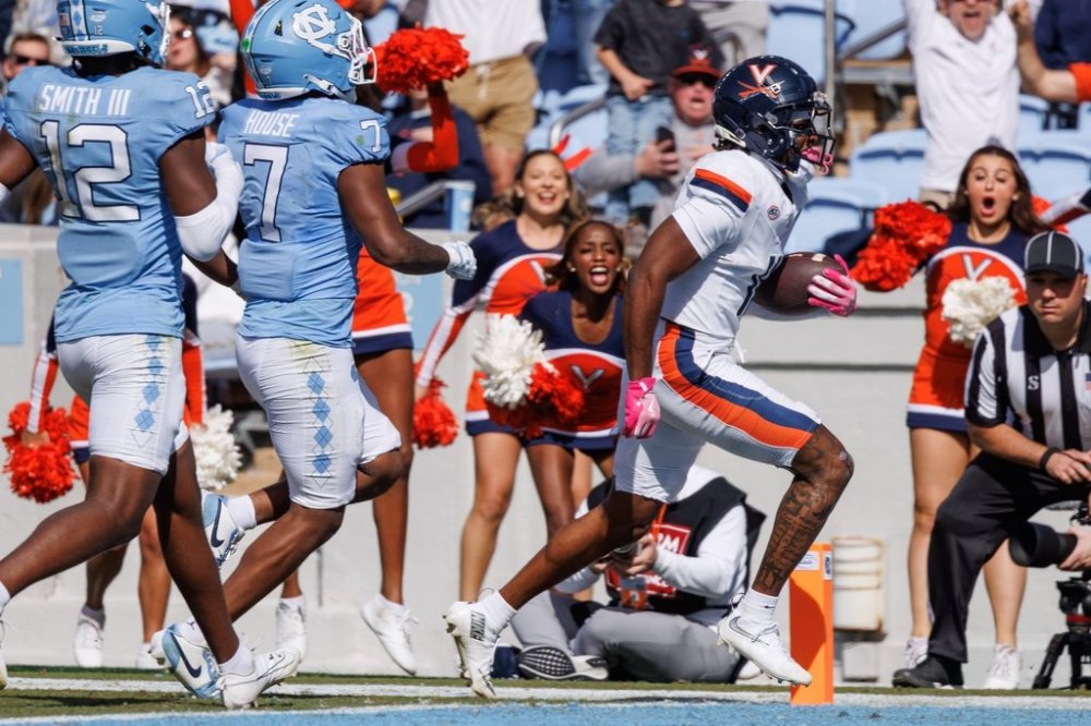 Virginia's Trell Harris (11) scores a touchdown ahead of North Carolina's Khmori House (7) and Greg Smith (12) during the first half of an NCAA college football game in Chapel Hill, N.C. Saturday, Oct. 25, 2025. (AP Photo/Ben McKeown)