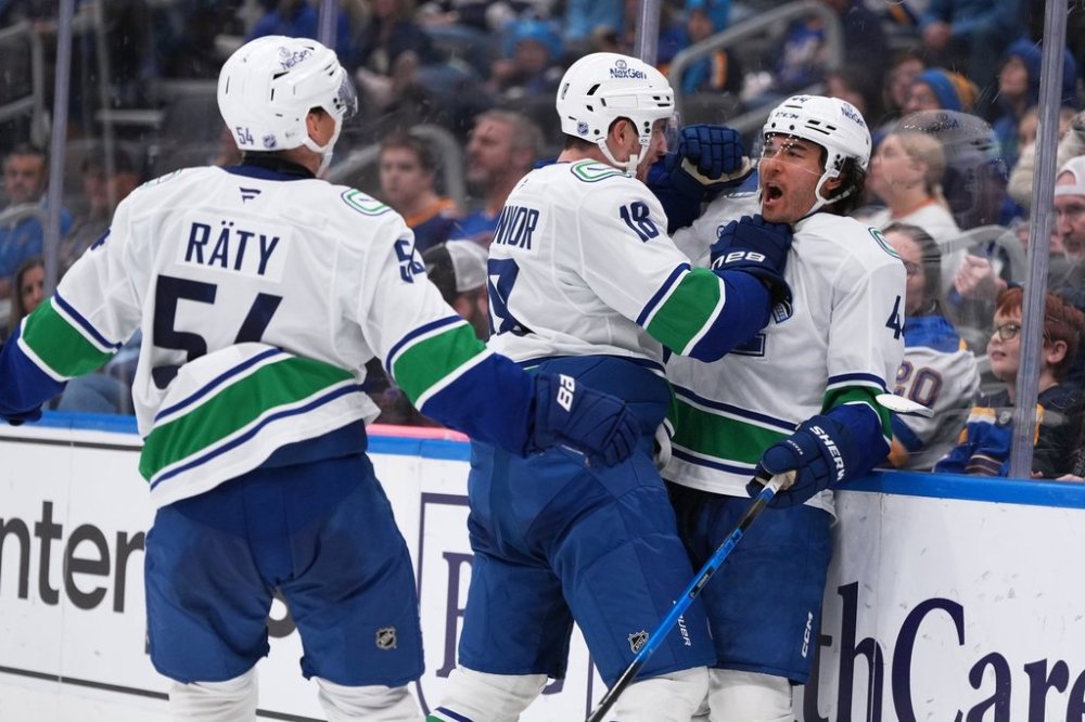 Vancouver Canucks' Kiefer Sherwood, right, is congratulated by Drew O'Connor (18) and Aatu Raty (54) after scoring a hat trick during the third period of an NHL hockey game against the St. Louis Blues Thursday, Oct. 30, 2025, in St. Louis. (AP Photo/Jeff Roberson)