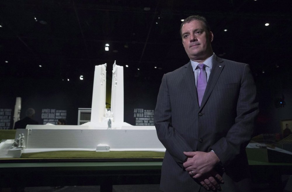Canadian military historian Tim Cook poses next to a maquette of the memorial at Vimy Ridge in the centre of the exhibition