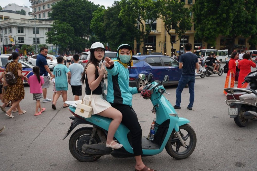 A Vietnamese motorcycle taxi ferries a customer on an EV scooter in the old squatter area in Hanoi, Vietnam, Friday, Sept. 1, 2025. (AP Photo/Vincent Thian)