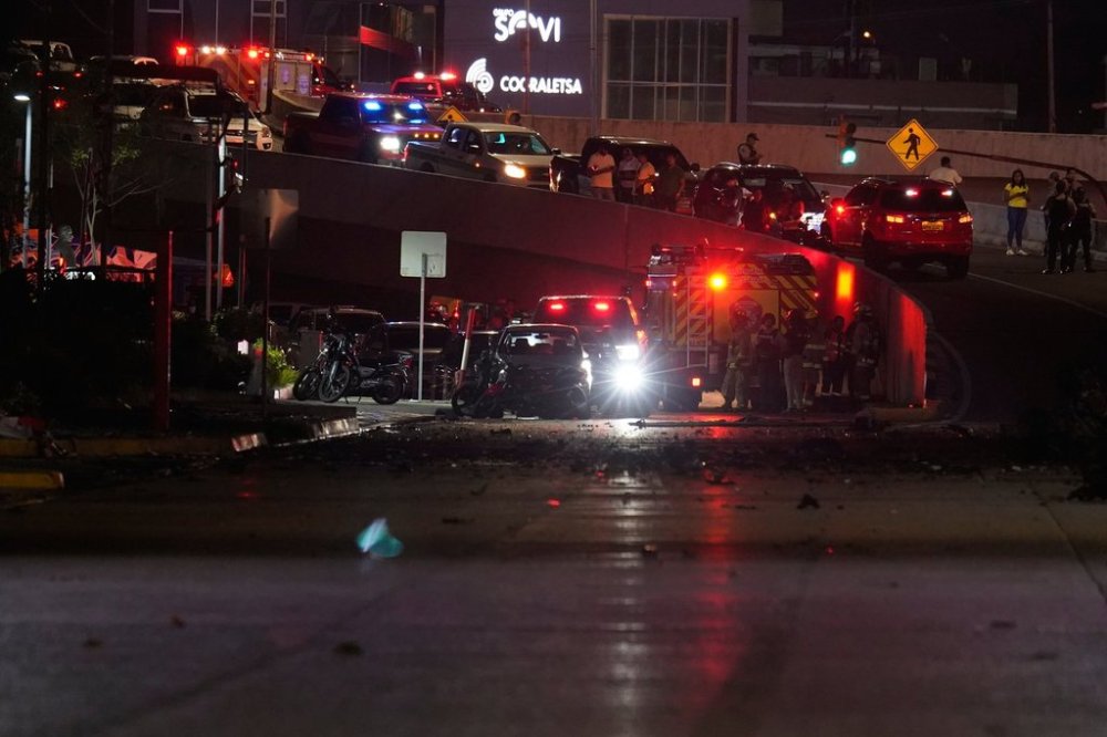 Police, firemen and security officials inspect the damage at the site of a car explosion on a shopping street in Guayaquil, Ecuador, Tuesday, Oct. 14, 2025. (AP Photo/Cesar Munoz)