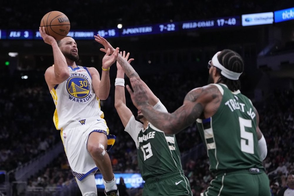 Golden State Warriors' Stephen Curry shoots past Milwaukee Bucks' Ryan Rollins and Gary Trent Jr. during the first half of an NBA basketball game Thursday, Oct. 30, 2025, in Milwaukee. (AP Photo/Morry Gash)