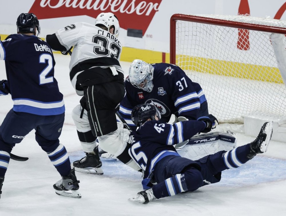 Winnipeg Jets goaltender Connor Hellebuyck (37) saves the shot from Los Angeles Kings' Brandt Clarke (92) as Cole Koepke (45) defends during first period NHL action in Winnipeg, Saturday, Oct. 11, 2025. THE CANADIAN PRESS/John Woods