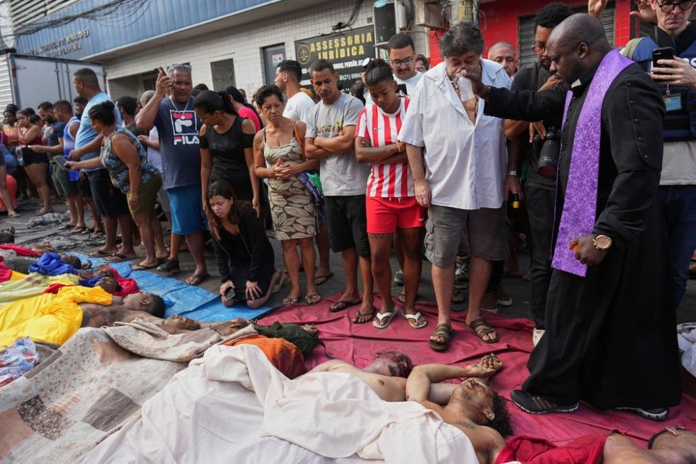 A priest blesses the bodies of people killed the day before during a police raid targeting the Comando Vermelho gang in the Complexo da Penha favela of Rio de Janeiro, Brazil, Wednesday, Oct. 29, 2025. (AP Photo/Silvia Izquierdo)