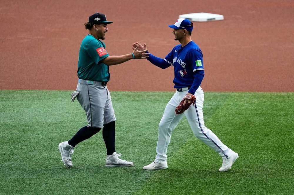 Seattle Mariners' Josh Naylor, left, greets Toronto Blue Jays' Andrés Giménez prior to Game 2 of baseball's American League Championship Series against the Toronto Blue Jays, Monday, Oct. 13, 2025, in Toronto. (AP Photo/David J. Phillip)