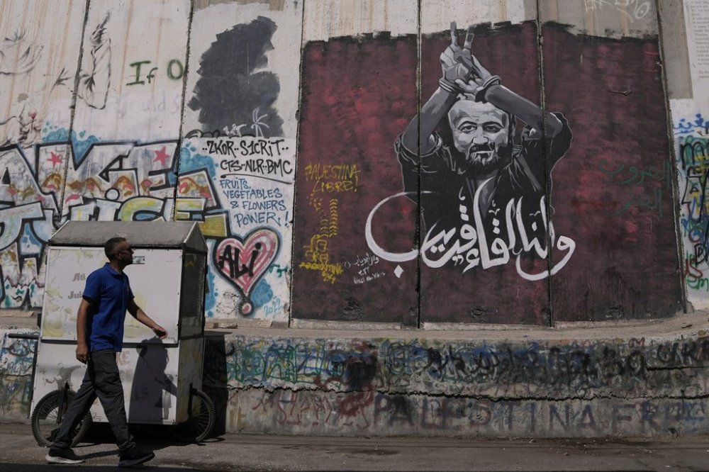 FILE - A man walks past a mural depicting the Palestinian leader Marwan Barghouti, with a message that reads in Arabic,