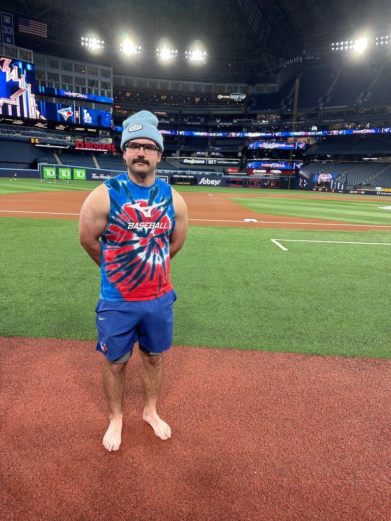Toronto Blue Jay's Davis Schneider stands on the field barefooted before baseball World Series workouts, Thursday, Oct. 30, 2025, in Toronto. (AP Photo/Ronald Blum)