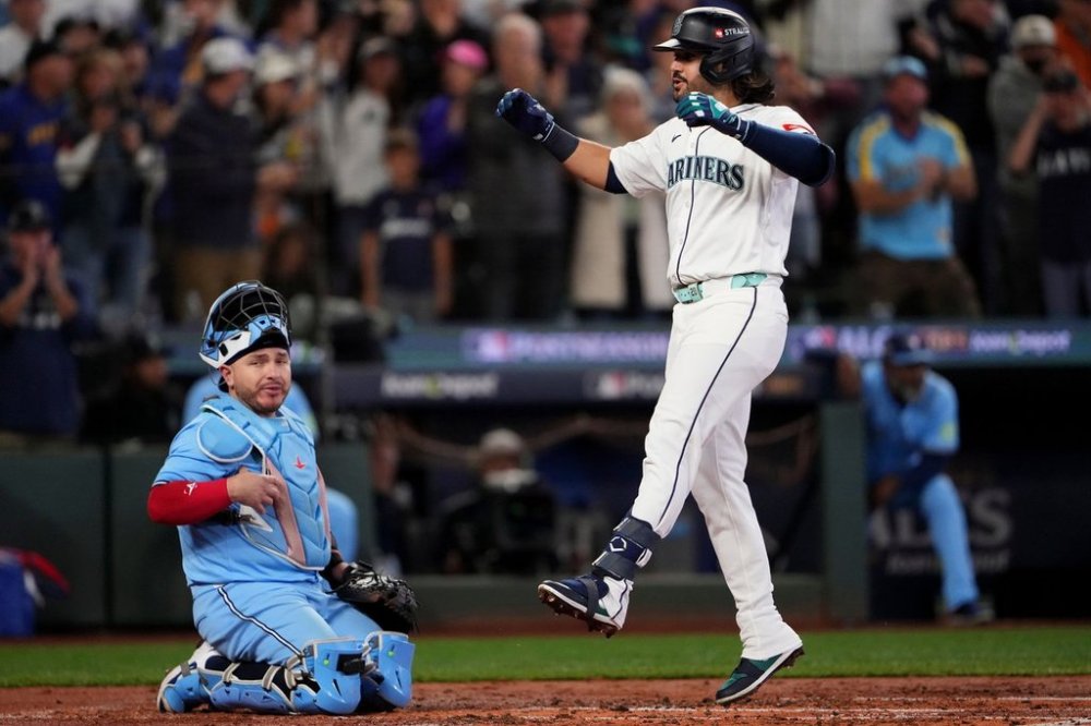 Seattle Mariners' Eugenio Suárez celebrates his solo home run during the second inning in Game 5 of baseball's American League Championship Series as Toronto Blue Jays Alejandro Kirk, left, look on, Friday, Oct. 17, 2025, in Seattle. (AP Photo/Lindsey Wasson)