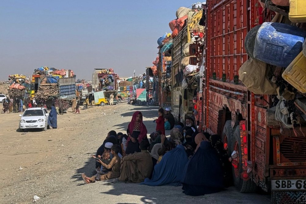 Afghan refugees sit beside trucks loaded with their belongings as they wait their turn to leave for their homeland through a border crossing point which partially opens following Oct.19 ceasefire on the outskirts of Chaman, a border town on the Pakistan Afghan border, Wednesday, Oct. 29, 2025. (AP Photo/H. Achakzai)