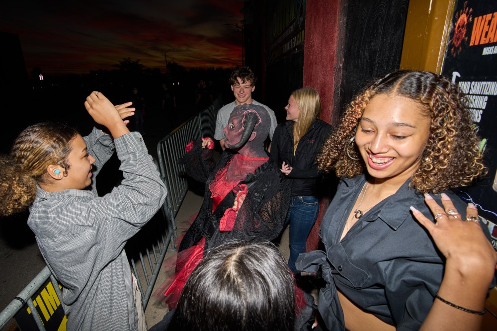 Rosey Washington, right, dances with friends before her performance at the Erebus Haunted House, Oct. 4, 2025, in Pontiac, Mich. (AP Photo/Ryan Sun)