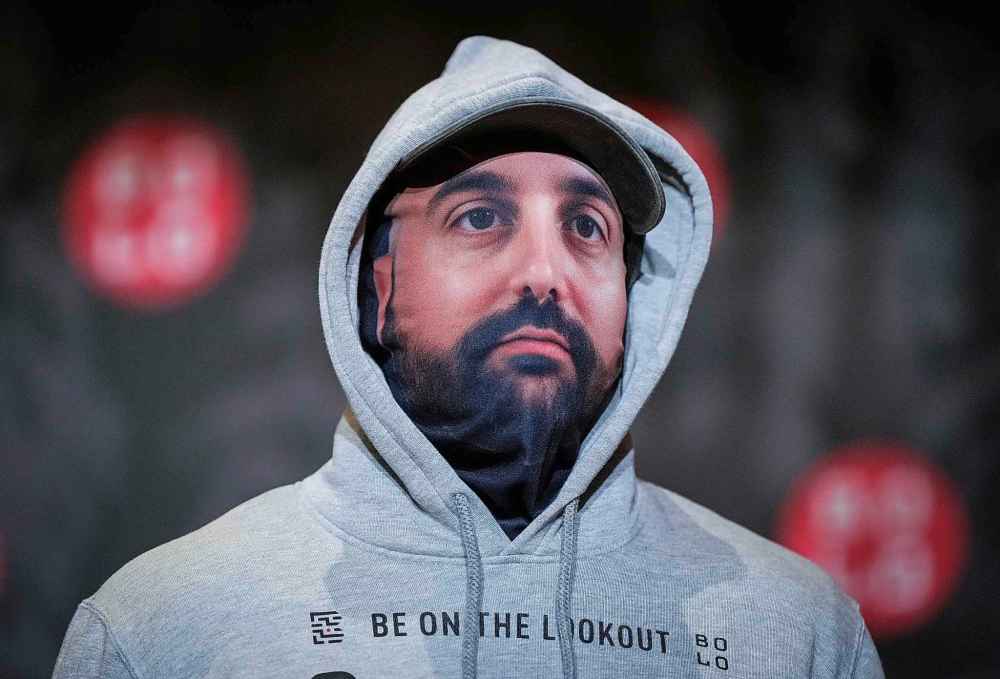 A police officer acting as a model wears a mask bearing the face of wanted fugitive Omid Mashinchi during a Bolo Program news conference, in Vancouver, on Wednesday, Oct. 8, 2025. The B.C. RCMP along with 15 other Canadian police agencies and the Bolo Program announced the top 25 wanted Canadian fugitives. THE CANADIAN PRESS/Darryl Dyck