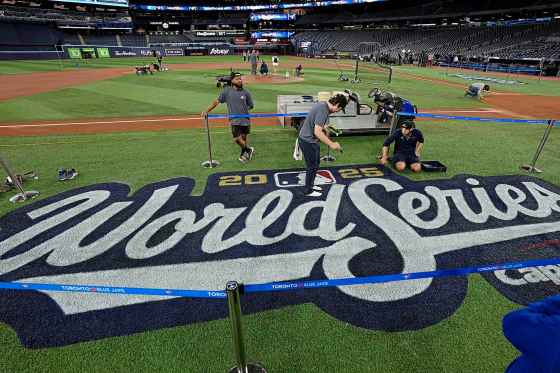 Toronto Blue Jays grounds crew members Coleton Miller, centre, and Jake Matthew, right, work on the World Series logo during a baseball media day Oct. 23 in Toronto. The Toronto Blue Jays face the Los Angeles Dodgers in Game 1 on Friday. (David J. Phillip / The Associated Press files)
