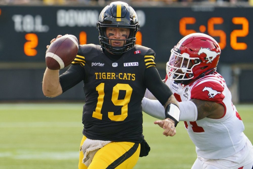 Hamilton Tiger Cats quarterback Bo Levi Mitchell (19) is pressured by Calgary Stampeders' Vyshonne Janusas (81) during first half CFL football game action in Hamilton, Ont., Saturday, Oct. 11, 2025. THE CANADIAN PRESS/Peter Power