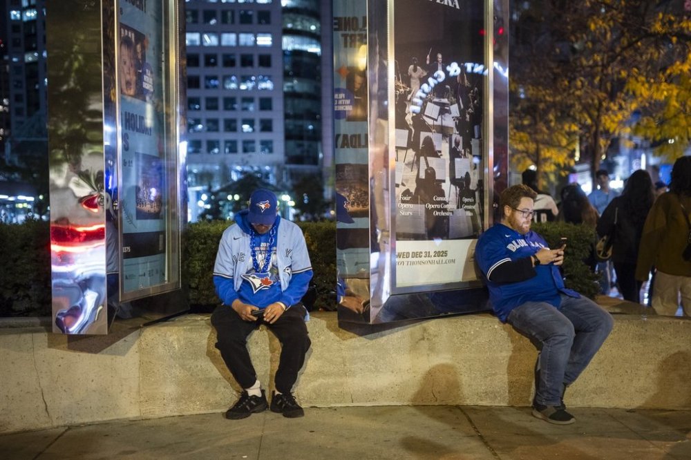 Baseball fans sit downtown following World Series Game 7 between the Toronto Blue Jays and Los Angeles Dodgers in Toronto on Sunday, November 2, 2025. THE CANADIAN PRESS/Nick Iwanyshyn