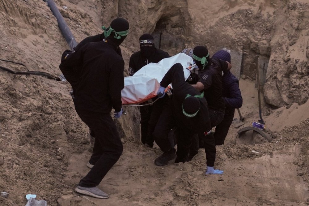 Hamas militants carry a white bag believed to contain a body, retrieved from a tunnel during a search for the remains of hostages in Hamad City, Khan Younis, southern Gaza, Tuesday, Oct. 28, 2025. (AP Photo/Jehad Alshrafi)