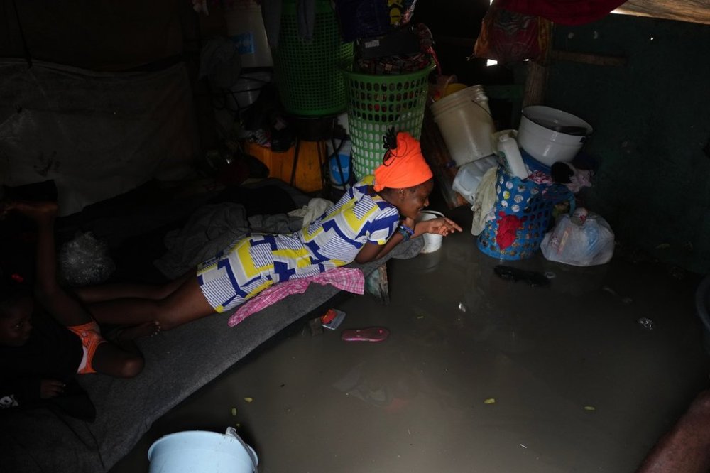 A woman lies inside a shack flooded by rain brought by Hurricane Melissa at a shelter for families displaced by gang violence in Port-au-Prince, Haiti, Wednesday, Oct. 29, 2025. (AP Photo/Odelyn Joseph)