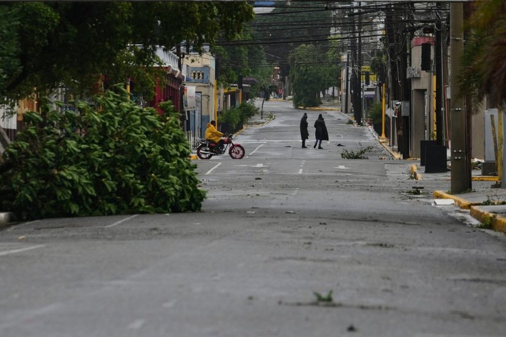 People walk in Kingston, Jamaica, as Hurricane Melissa approaches, Tuesday, Oct. 28, 2025. (AP Photo/Matias Delacroix)