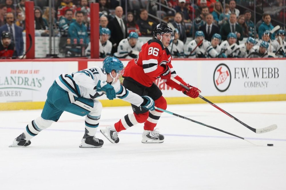 New Jersey Devils' Jack Hughes, right, competes for the puck with San Jose Sharks' Collin Graf, left, during the second period of an NHL hockey game Friday, Oct. 24, 2025, in Newark, N.J. (AP Photo/Pamela Smith)