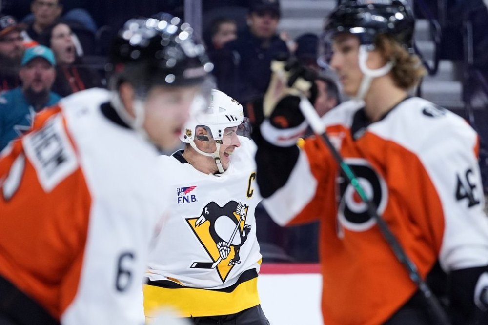 Pittsburgh Penguins' Sidney Crosby, centre, reacts past Philadelphia Flyers' Travis Sanheim, left, and Trevor Zegras after scoring a goal during the third period of an NHL hockey game, Tuesday, Oct. 28, 2025, in Philadelphia. (AP Photo/Matt Slocum)
