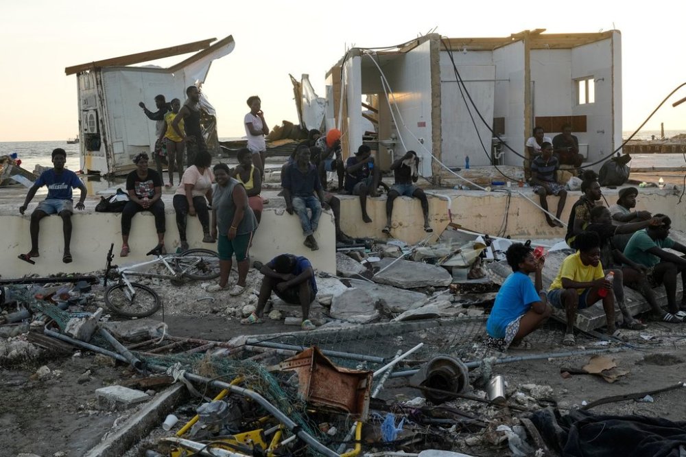 People gather among debris near a bridge in Black River, Jamaica, Thursday, Oct. 30, 2025, in the aftermath of Hurricane Melissa. (AP Photo/Matias Delacroix)