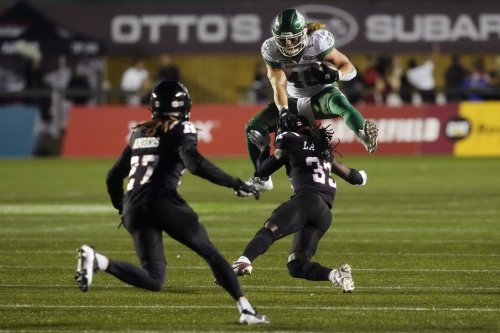 Saskatchewan Roughriders running back A.J. Ouellette (45) hurdles Ottawa Redblacks defensive back Deandre Lamont (33) as teammate defensive back King Ambers looks on during second half CFL action in Ottawa, Friday, Oct. 3, 2025.  THE CANADIAN PRESS/Adrian Wyld